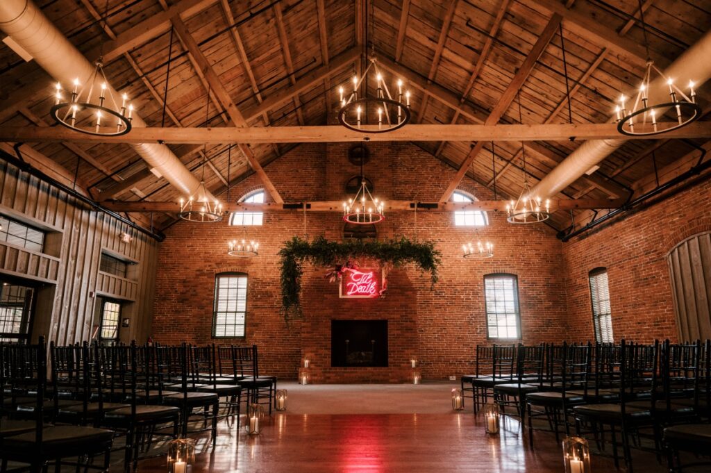 reception and ceremony space at the cork factory hotel in Lancaster PA. Pink neon "Til Death" sign. Moody industrial wedding ceremony with modern chandeliers 
