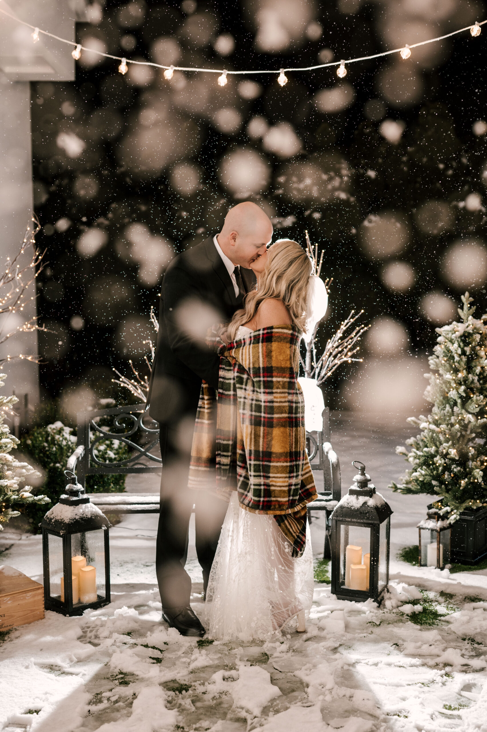 Couple kisses in the snow at Perona Farms Refinery. Night shot from december wedding in Andover, New Jersey