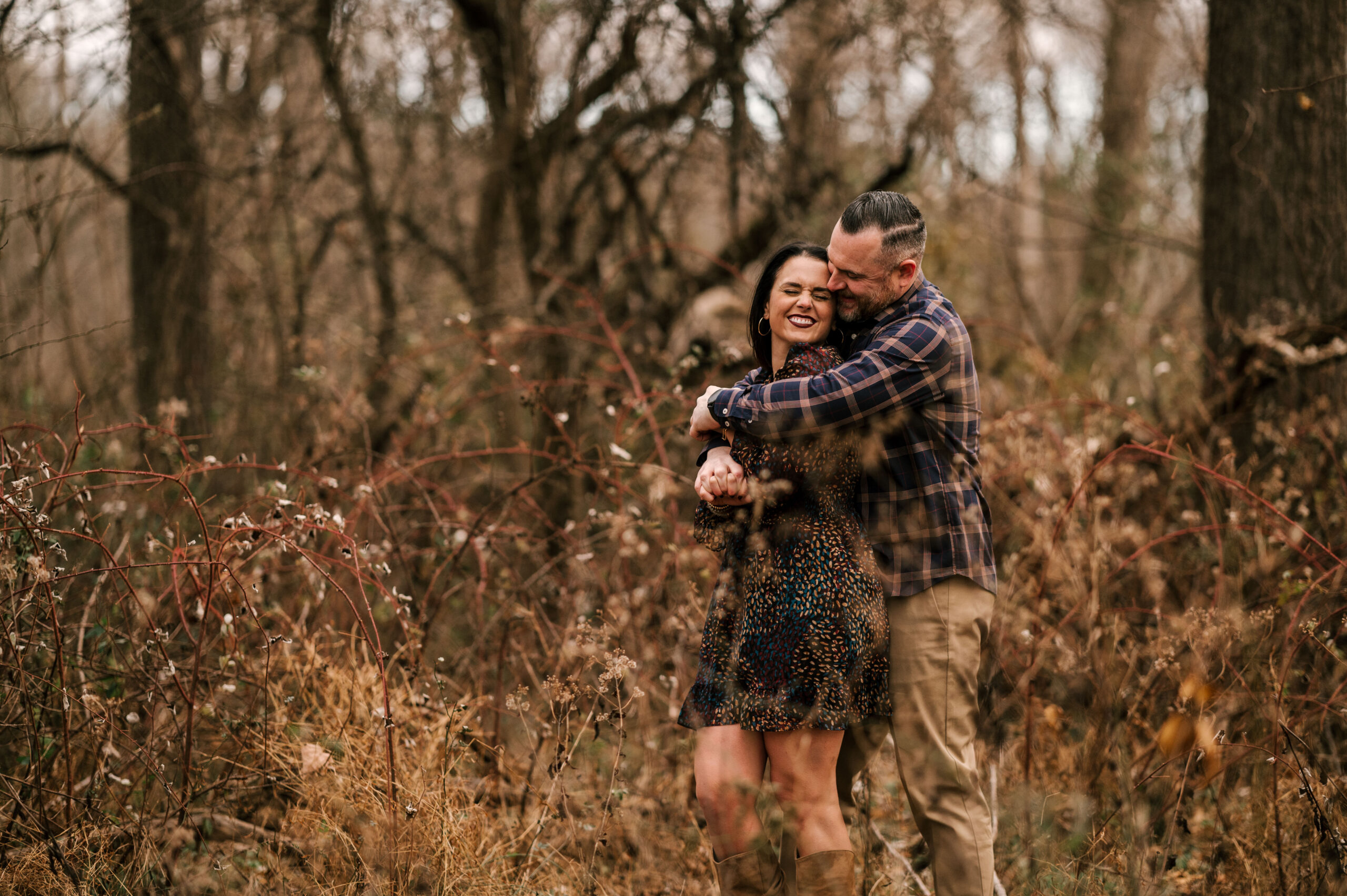 Couple laughs through meadow during Fall engagement session in November at Jockey Hollow Park in Morristown New Jersey
