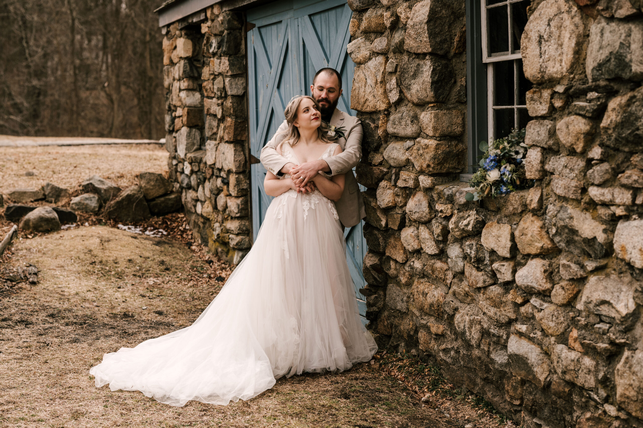 bride and groom standing in front of blue door and stone building at Waterloo village in stanhope new jersey