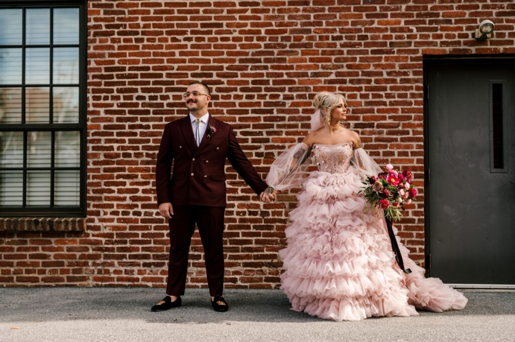 Cork Factory Hotel wedding couple in front of industrial brick wall. Bride in Pink dress