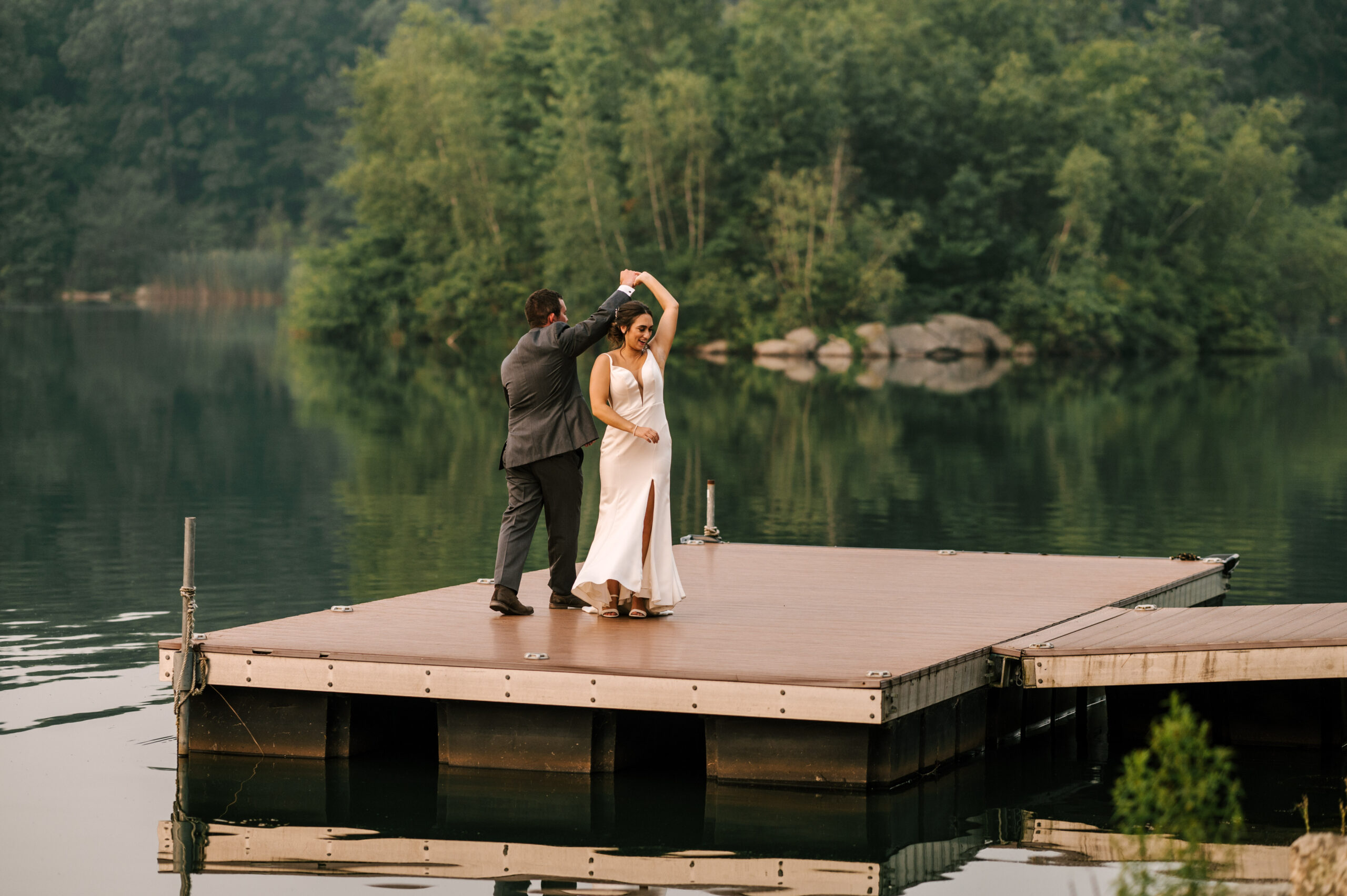 Bride and Groom dances on the dock at Rock Island lake Club overlooking the lake at sunset in Sparta New Jersey