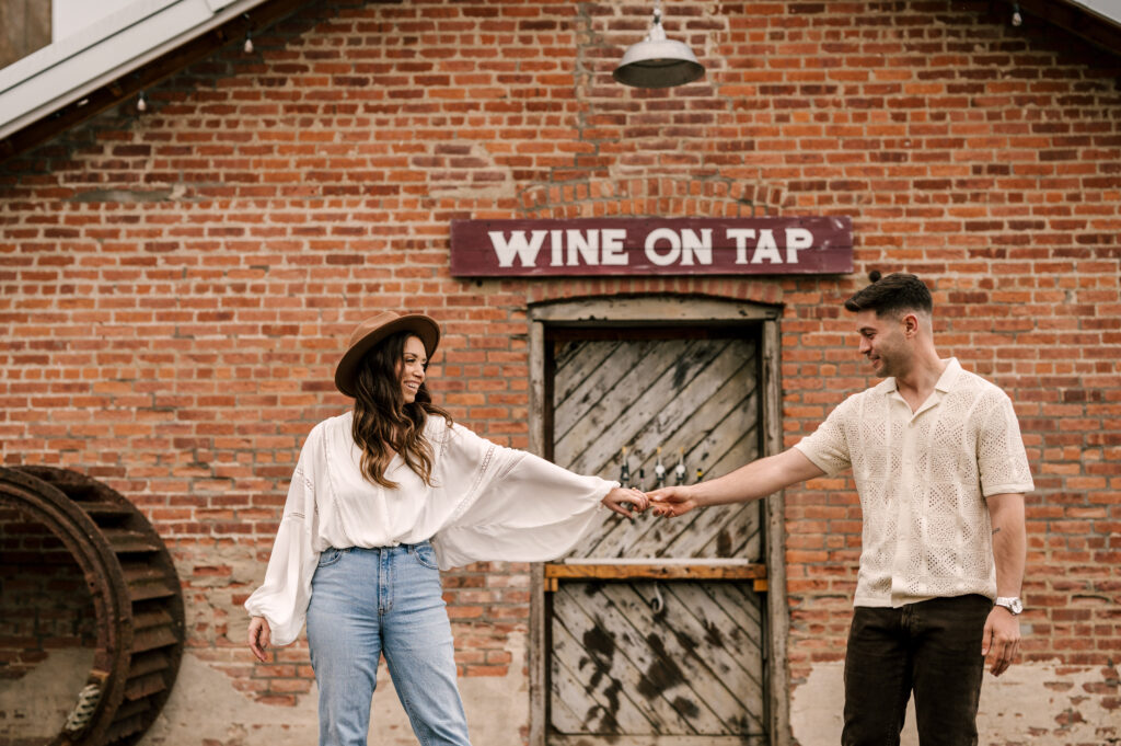 Couple posed for engagement session at City Winery Hudson Valley NY in Montgomery New York in front of Wine on Tap sign