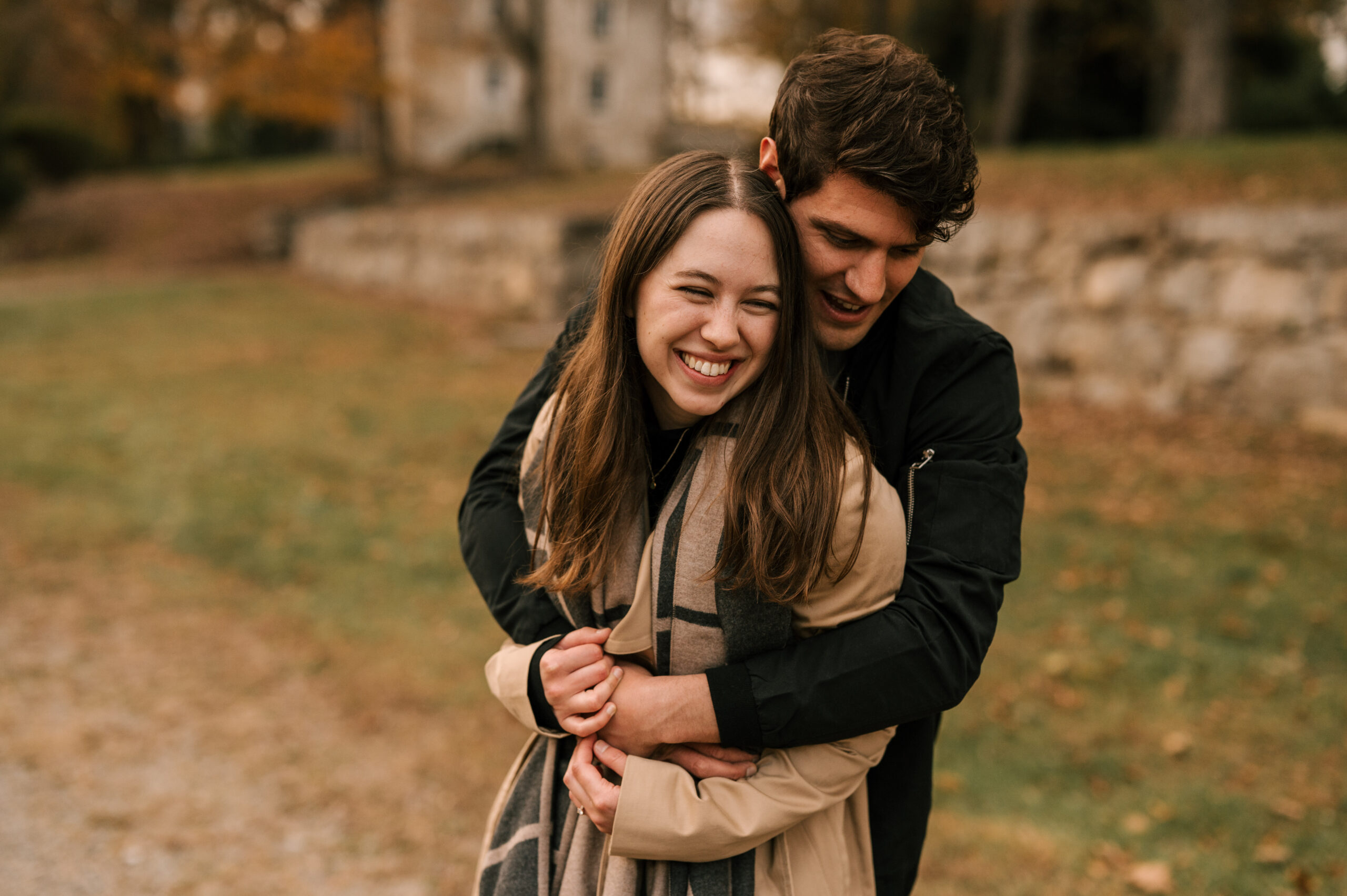 Couple embraces and laughs during october fall engagement session at historical waterloo village in stanhope new jersey