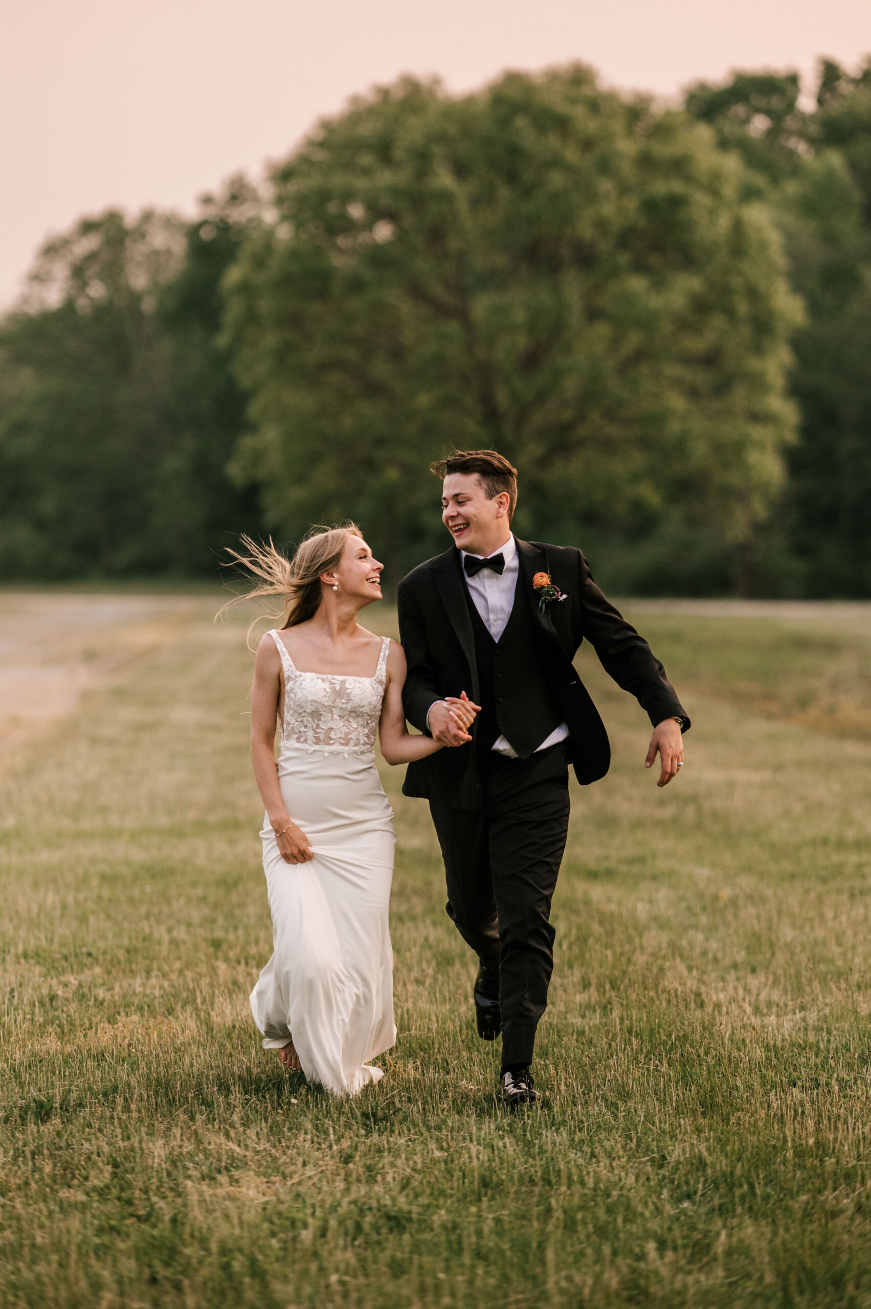 bride and groom running through the field at sunset at Conservatory at Sussex County Fairgrounds in Augusta New Jersey