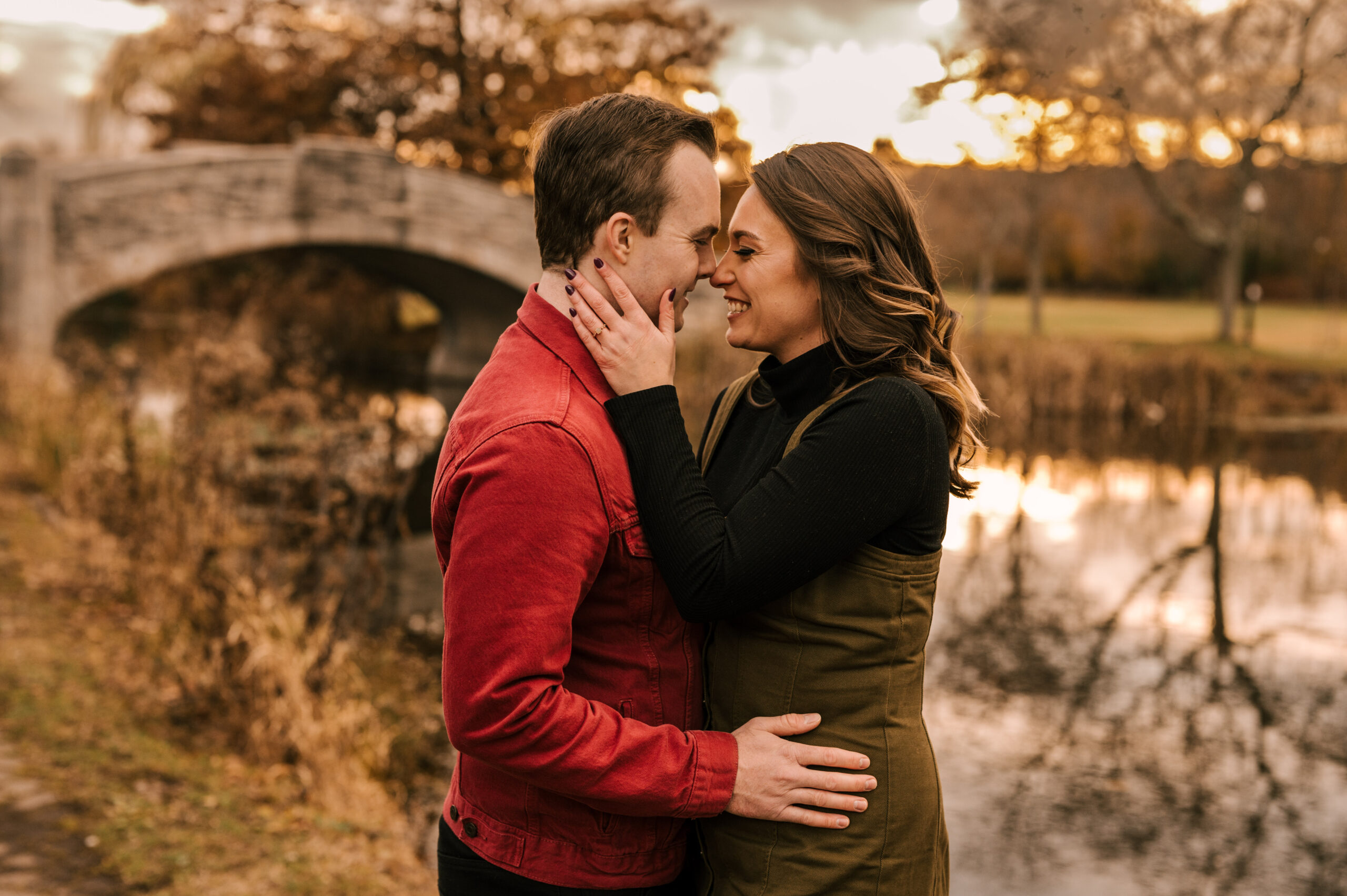 couple in love by the bridge at verona park in new jersey with fall foliage and a golden hour sunset