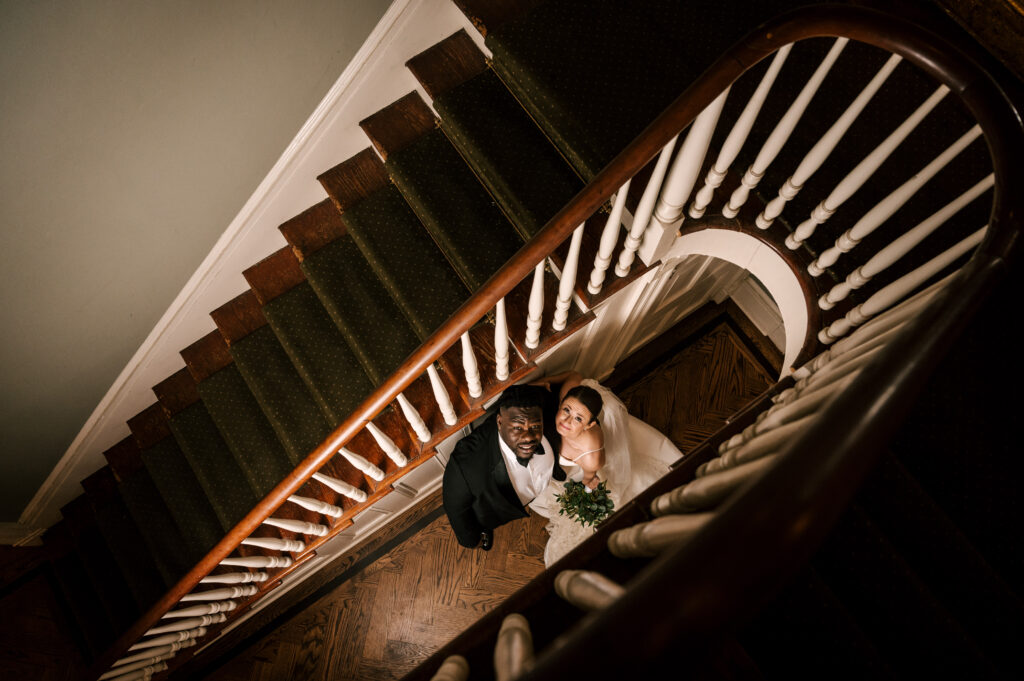 bride and groom in spiral wooden staircase aerial view at david's country inn in hackettstown new jersey