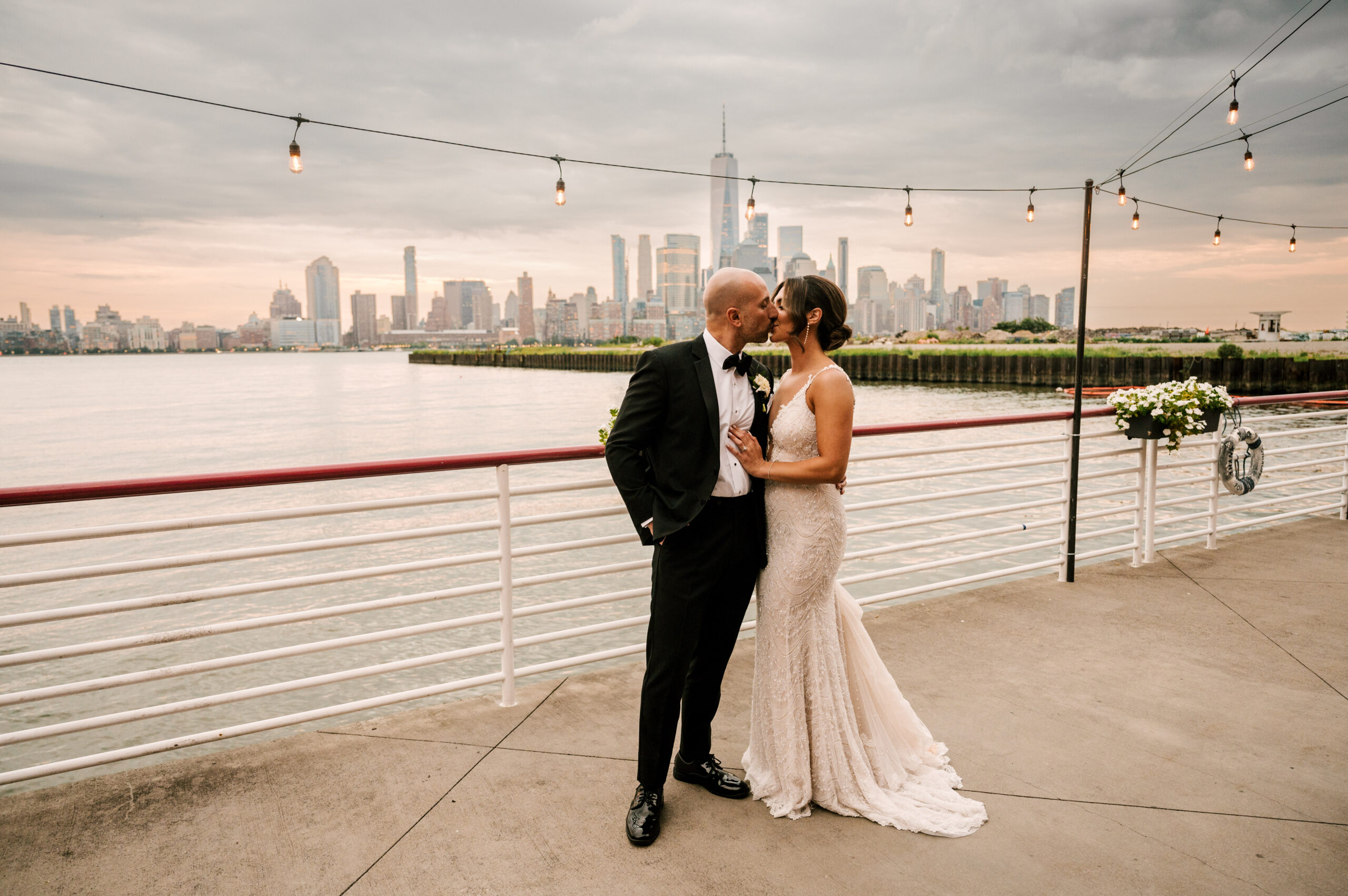 The newlyweds kissing against the New York City skyline at Battello