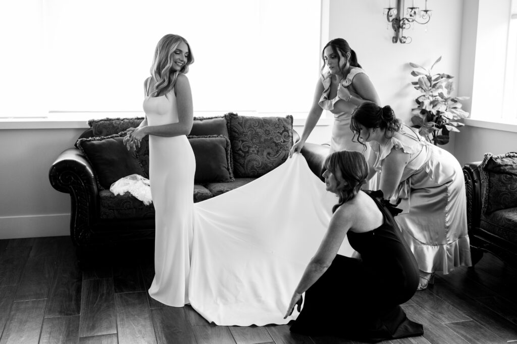 The bridemaids adjusting the bride's dress while getting ready for the ceremony at Perona Farms.