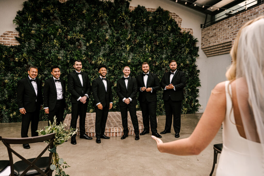 The groomsmen smiling as they take a first look at the bride before the cermony at Perona Farms.