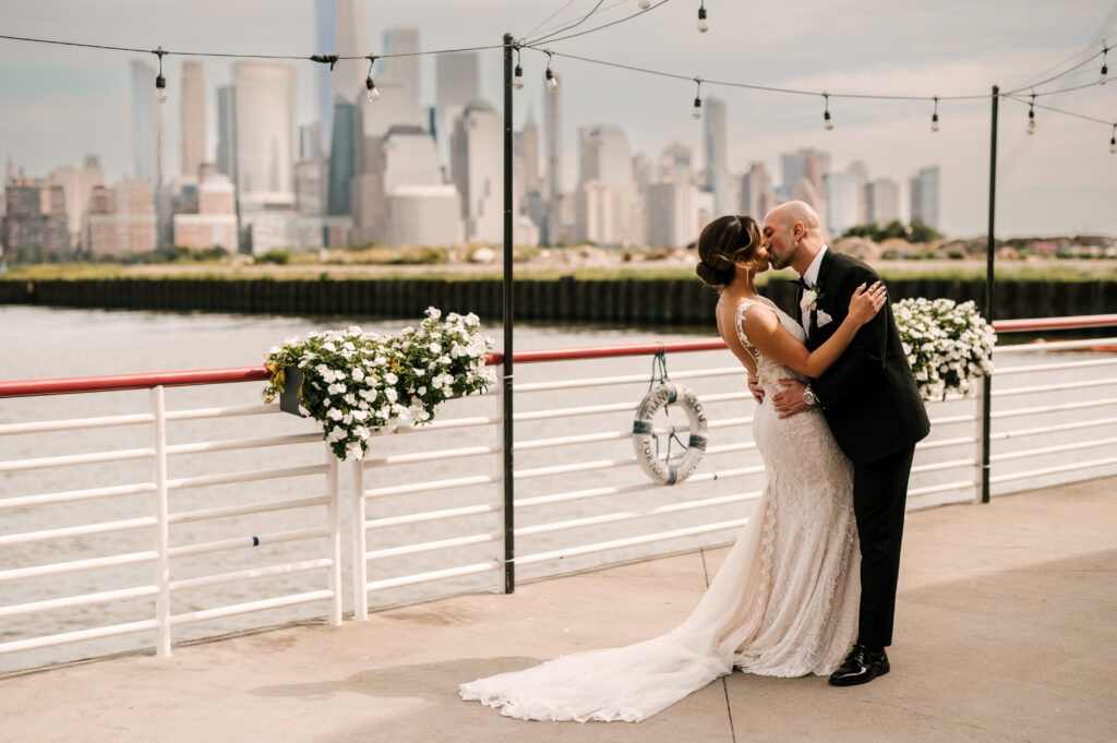 The newlyweds sharing a kiss on the pier at Battello against the New York City skyline.