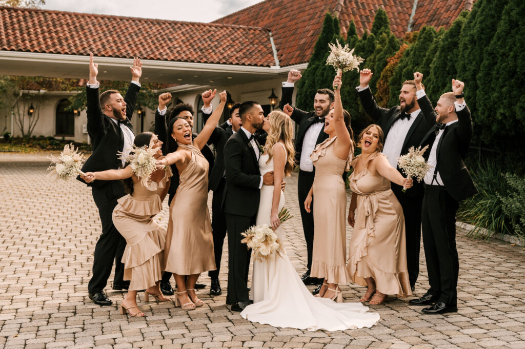 The bridesmaids and groomsmen cheering the bride and groom on as they share a kiss.