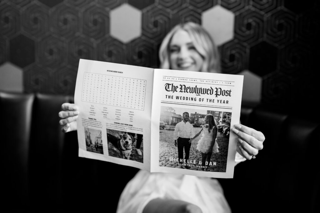 The bride smiling while holding a newspaper about her wedding at the Refinery at Perona Farms.