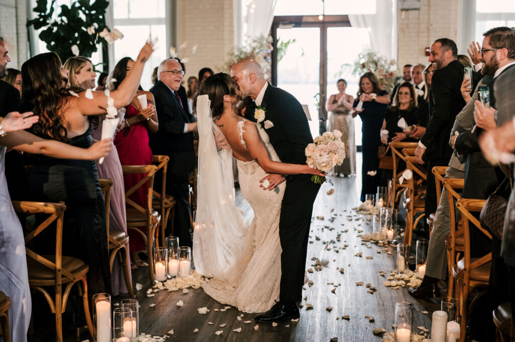 The groom dip kissing the bride half-way back down the aisle after the ceremony at Battello in Jersey City.