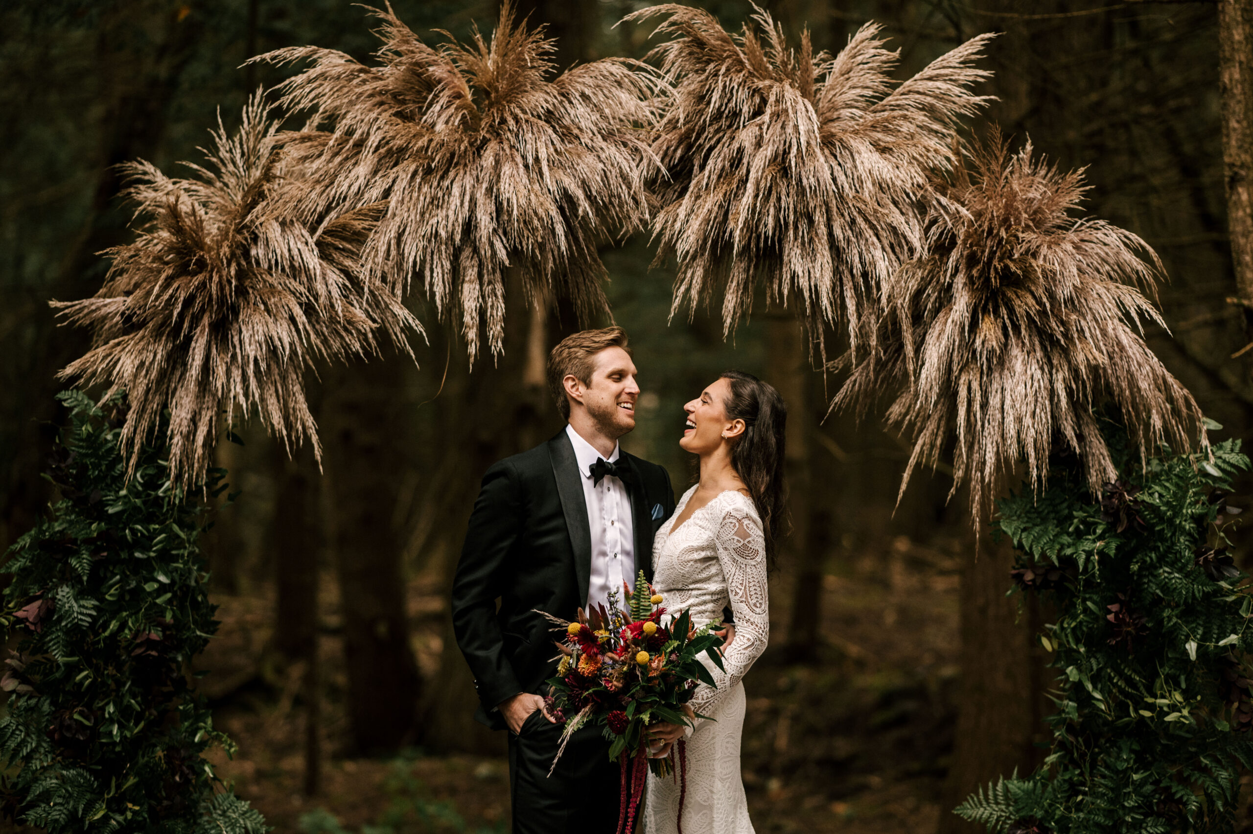 Bride and groom laughing under ceremony archway at Windham Manor in New York State