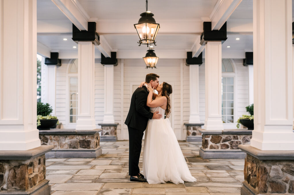 The newlyweds sharing a kiss outside of the reception space at the Ryland Inn/