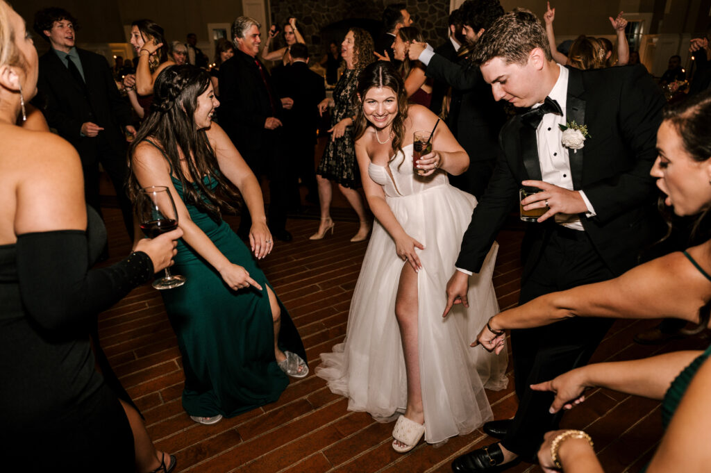 The newlyweds smiling as they happily dance with their bridesmaids and guests.