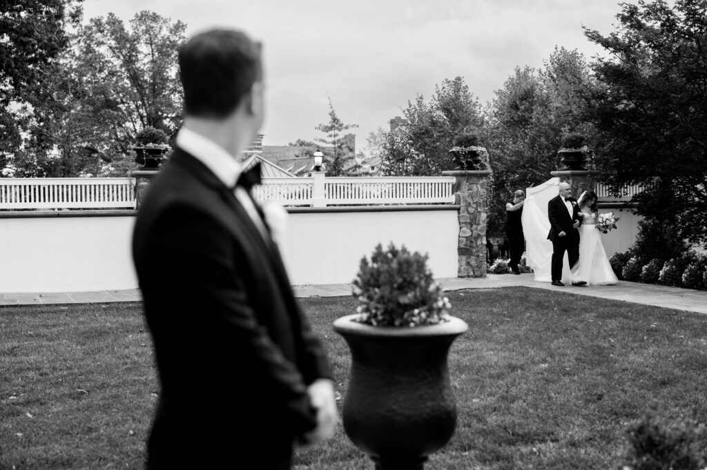 The groom looking on as the bride's father begins walking her down the aisle during the ceremony at the Ryland Inn.