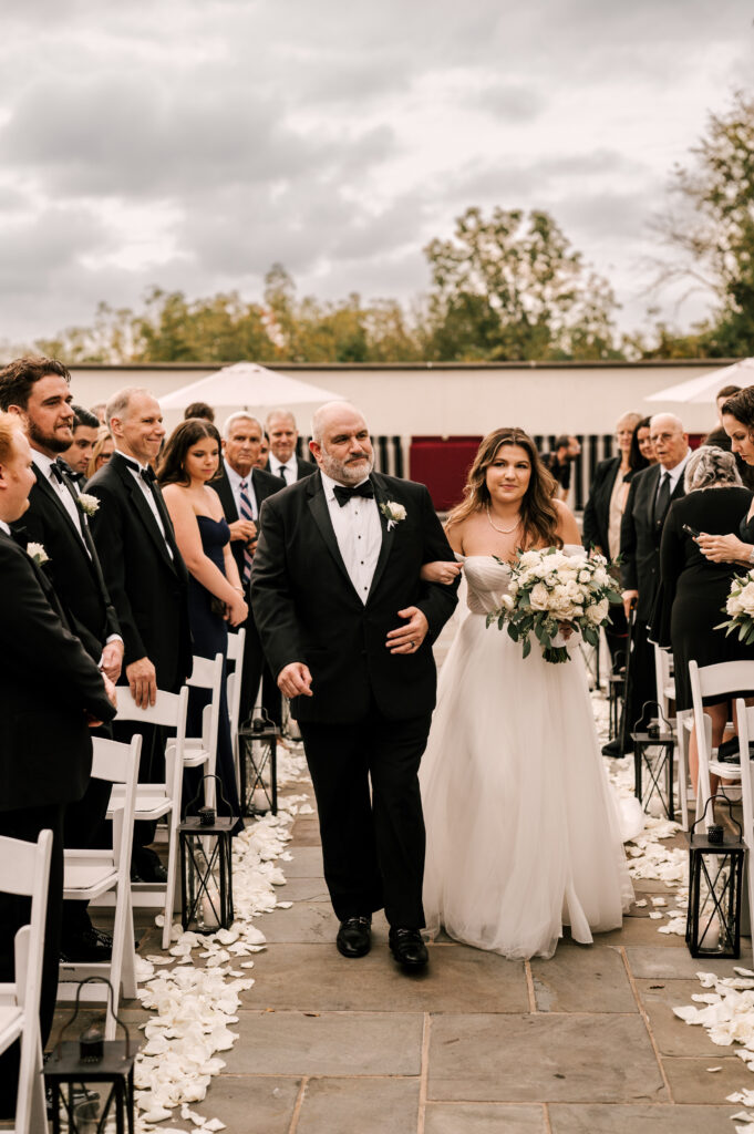 The father of the bride walking his daughter down the aisle during the ceremony at the Ryland Inn.