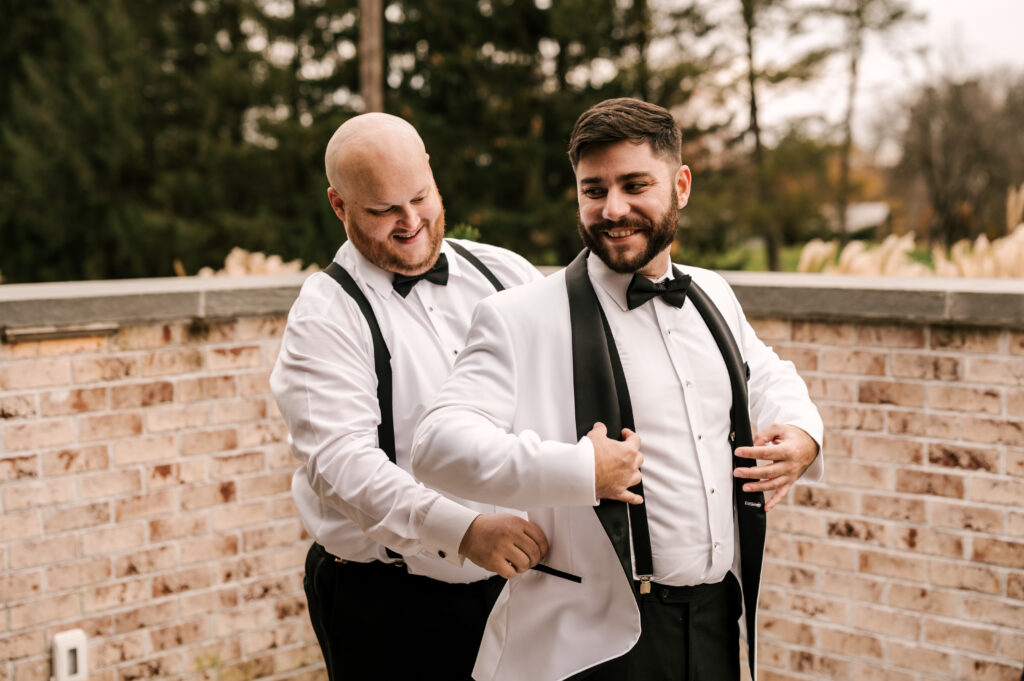 The groom's best man helping him put on his jacket before the ceremony.