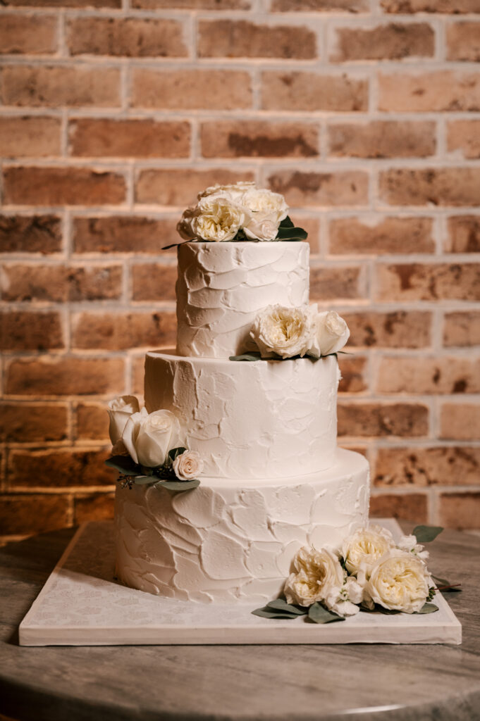 The wedding cake decorated with flowers for the reception at Perona Farms Refinery.