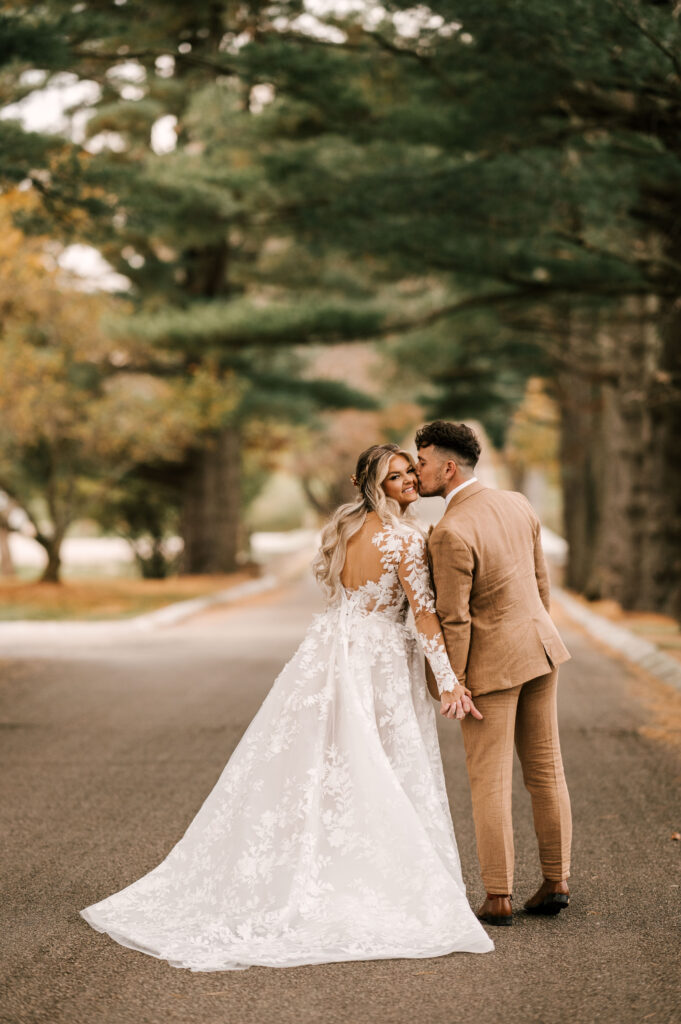 The bride leaning in as the groom kisses her cheek and they hold hands at Ashford Estate.