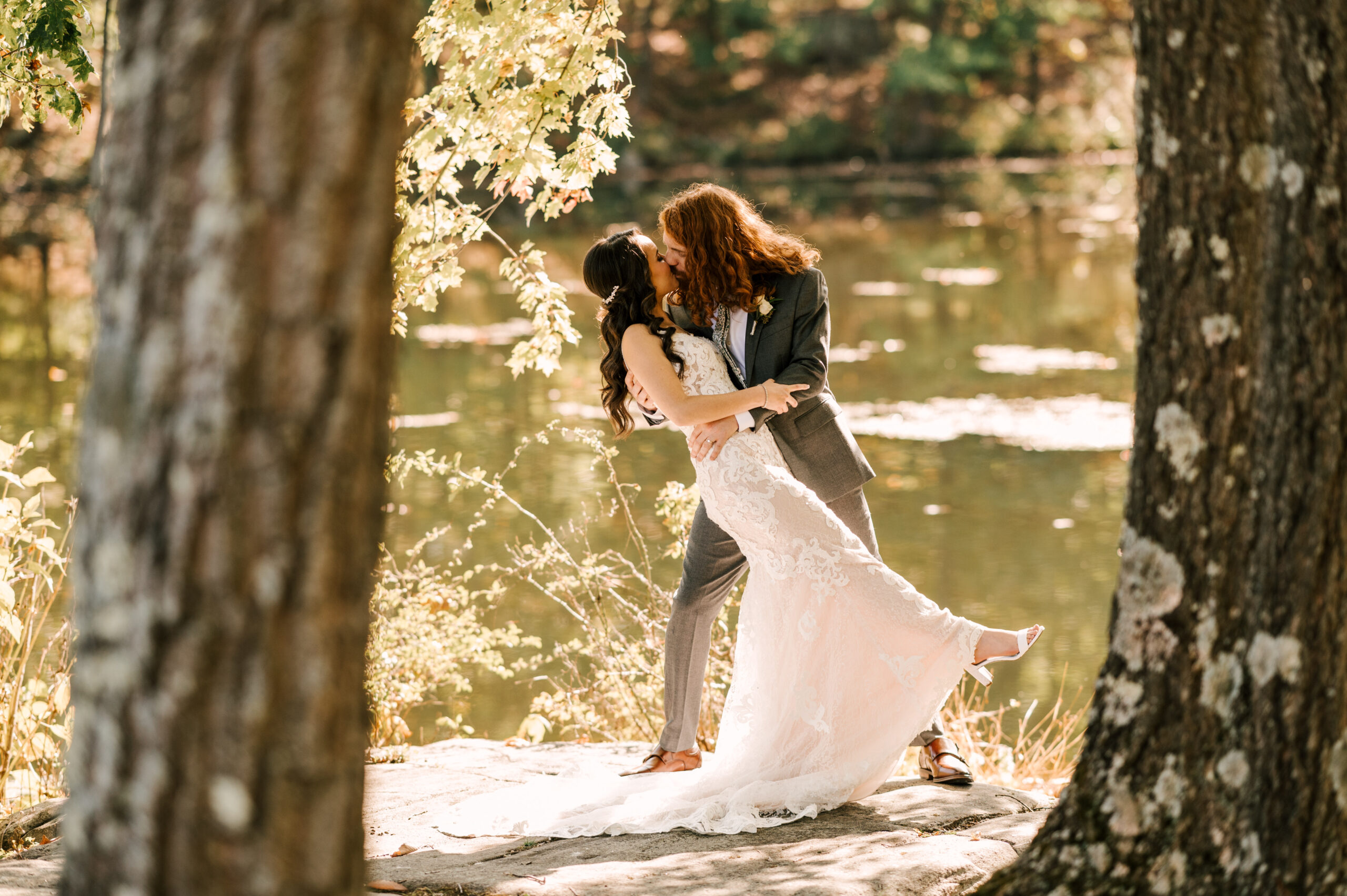 The groom dipkissing the bride in front of the lake at Perona Farms Refinery.