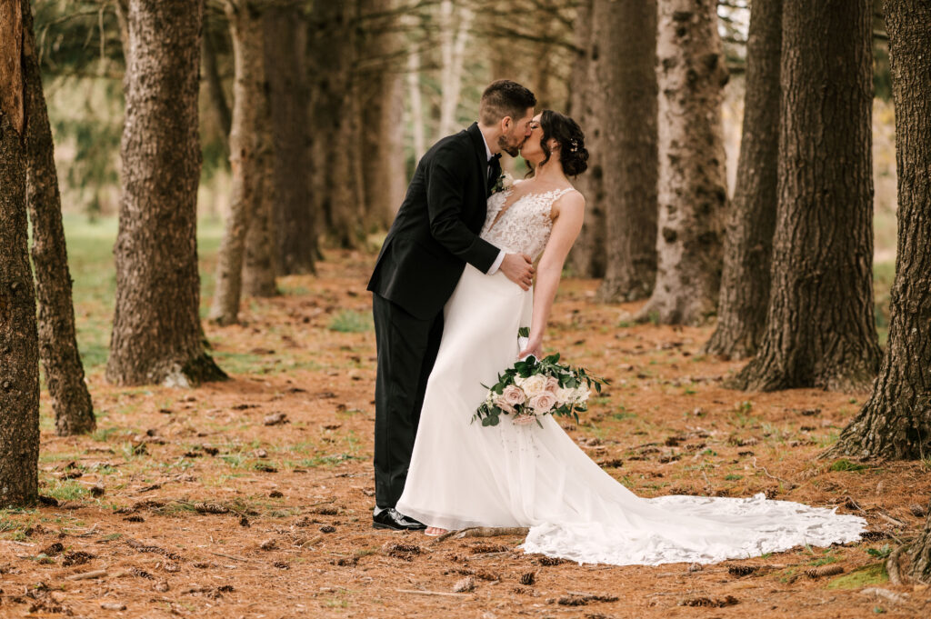 The bride and groom dip-kissing in the woods at Perona Farrms Reserve.