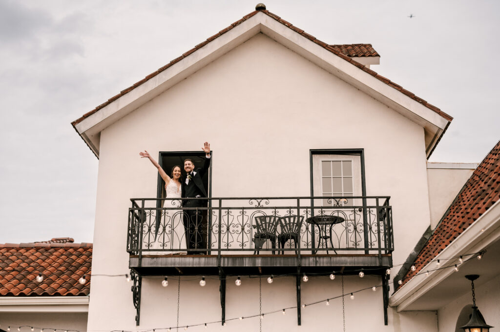 The couple smiling and waving from a balcony at Perona Farms Reserve.