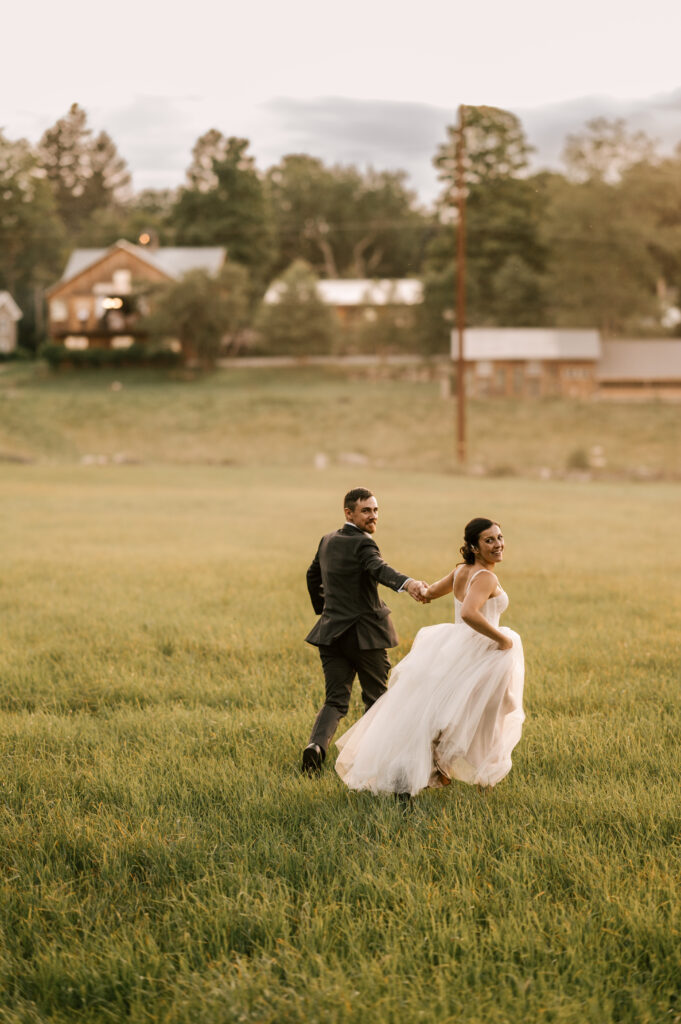 The couple smiling and running through the grass at Wallenpaupack Creek Farm.