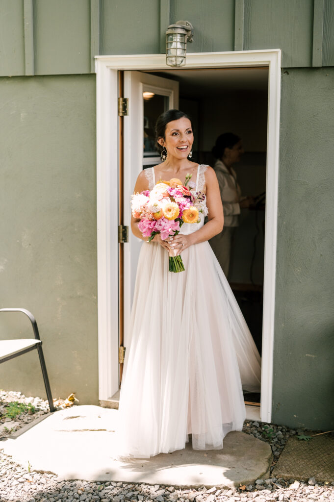 The bride smiling and holding her bouquet as she walks outside after getting ready at Wallenpaupack Creek Farm.