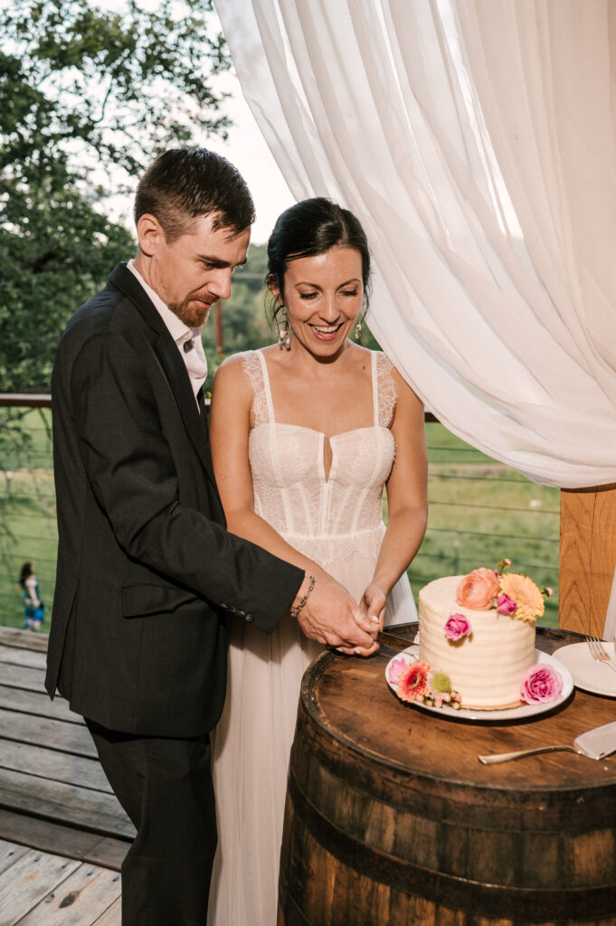The bride and groom smiling as they cut the cake at their reception at Wallenpaupack Creek Farm.