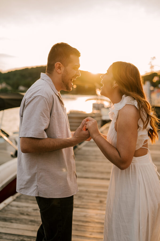 The couple giggling and holding hands excitedly during sunset on the dock on Lake Mohawk.