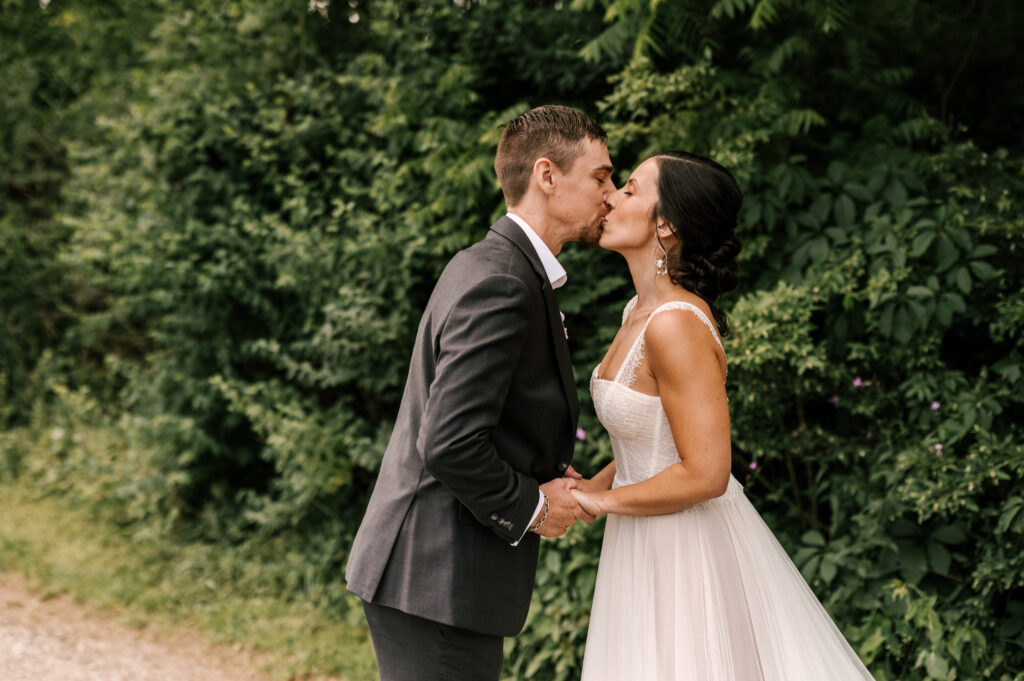 The bride and groom holding hands and sharing a kiss during their first look at Wallenpaupack Creek Farm.