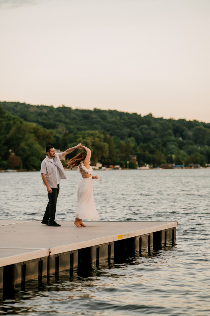 The groom-to-be twirling his fiancée on the edge of the dock on Lake Mohawk.