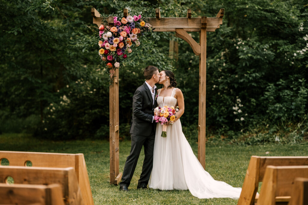 The couple sharing a kiss under the arch after the ceremony at Wallenpaupack Creek Farm.