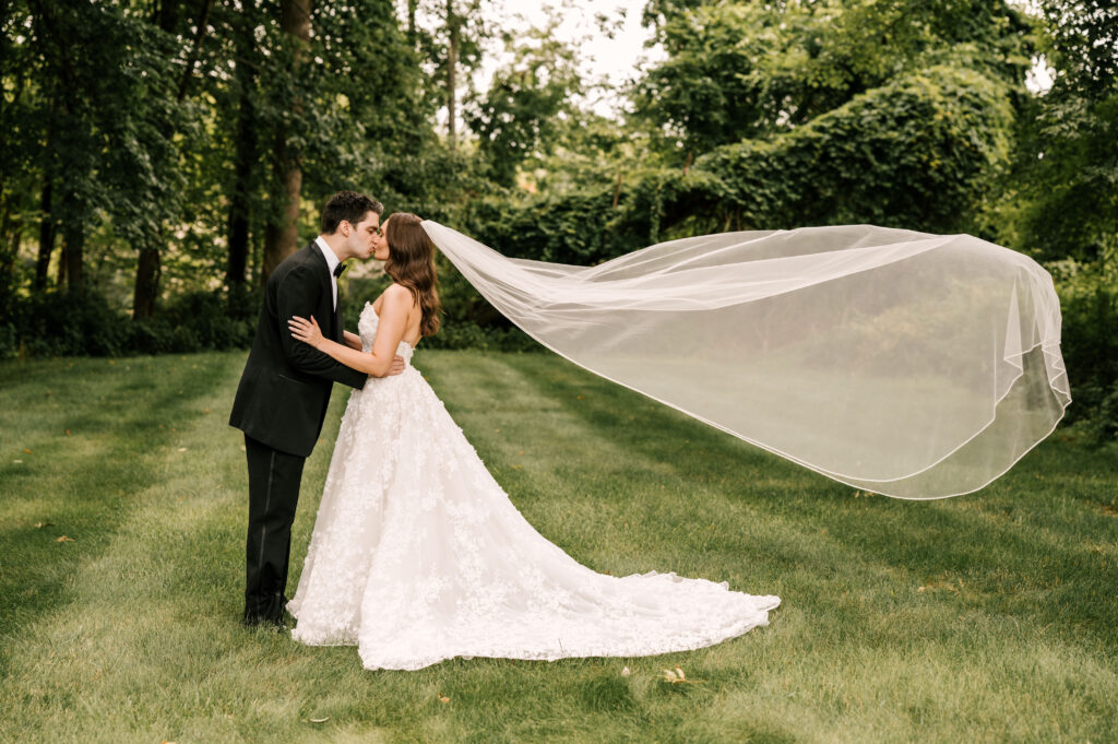 The couple kissing as the bride's veil flows in the wind behind them.