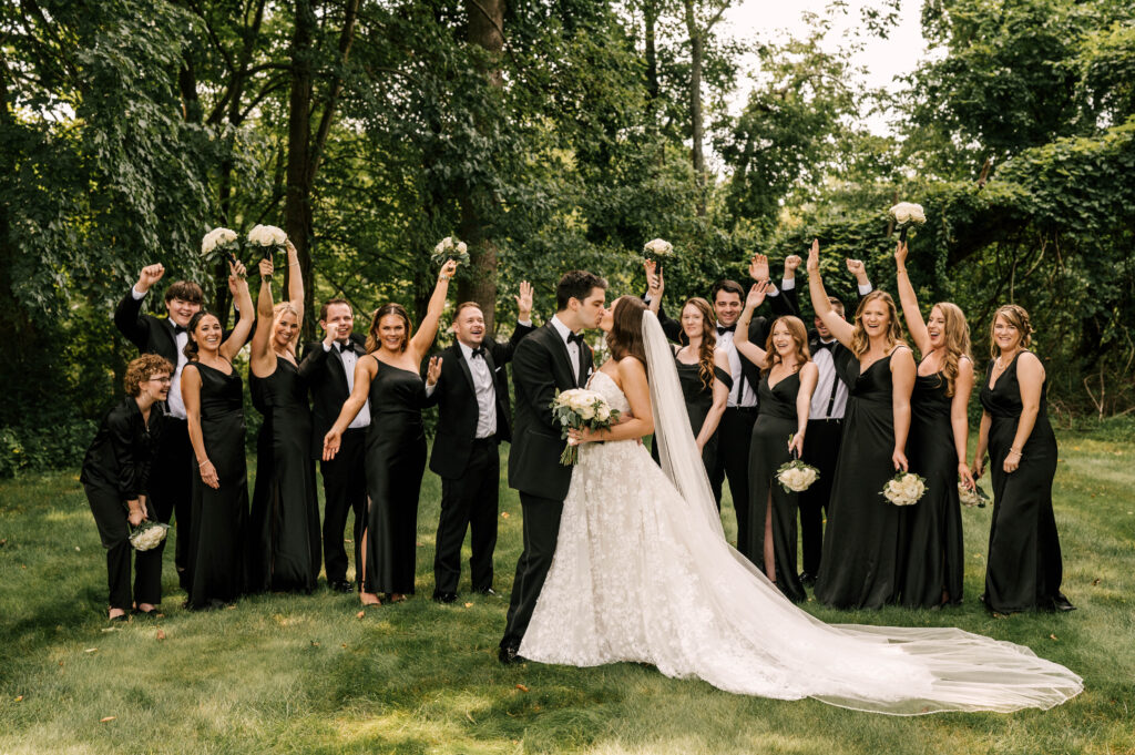 The bridal party cheering doe the bride and groom as they kiss at Perona Farms Refinery.