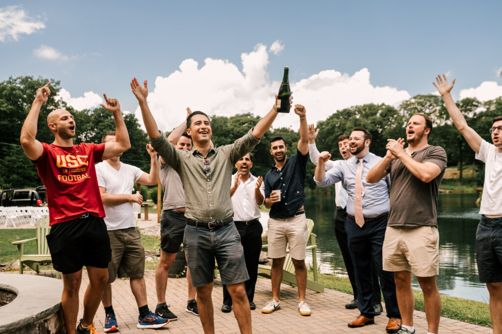The groom and his friends cheering and popping open a bottle at at Rock Island Lake Club.
