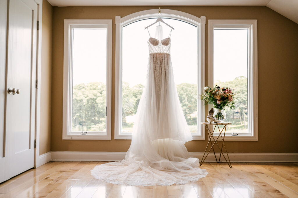 The bride's dress hanging in a windowsill before the ceremony at Rock Island Lake Club.