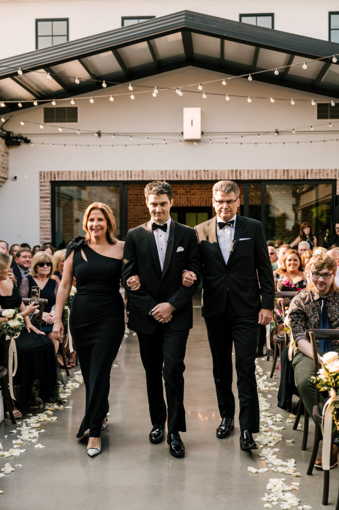 The groom's mother and father walking their son down the aisle at Perona Farms Refinery.