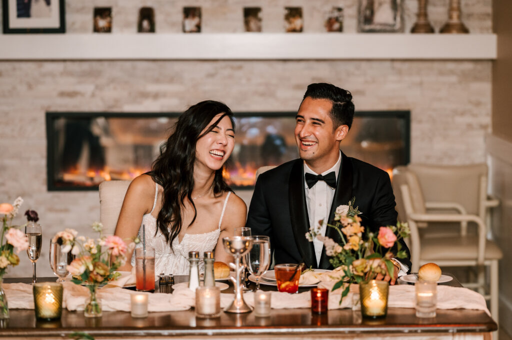 The newlyweds laughing together at their table during the reception at Rock Island Lake Club.