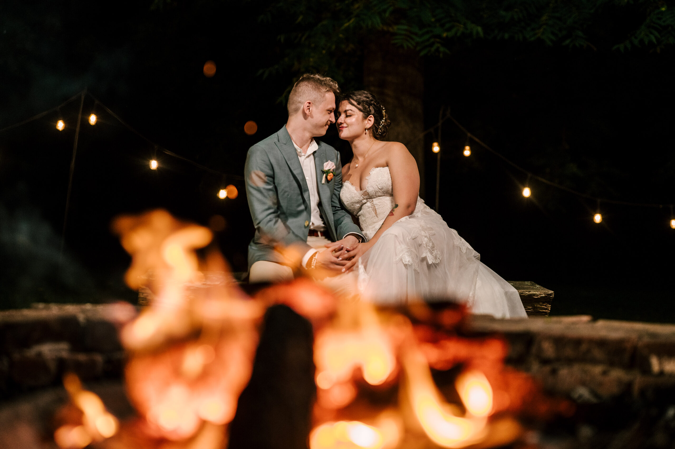 The bride and groom sharing an intimate moment by a fire pit outside at Waterloo Village.