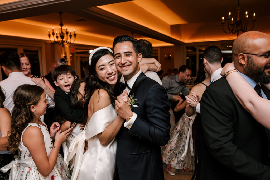 The newlyweds hugging as guests dance around them during the reception at Rock Island Lake Club.