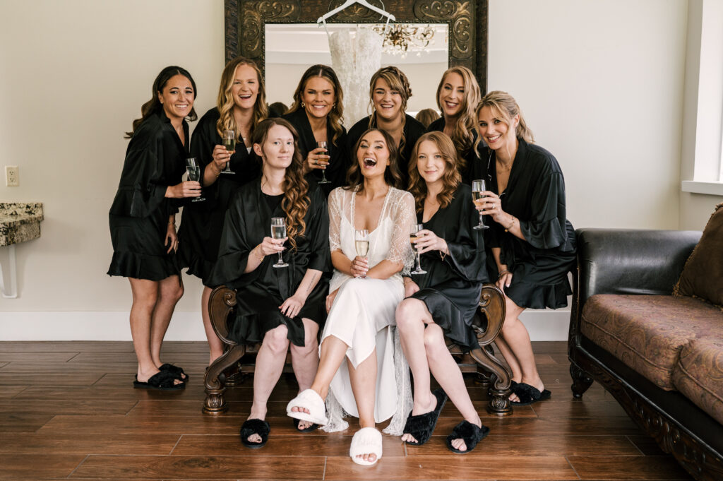The bride and her bridesmaids smiling and sharing a glass of champagne at Perona Farms Refinery.