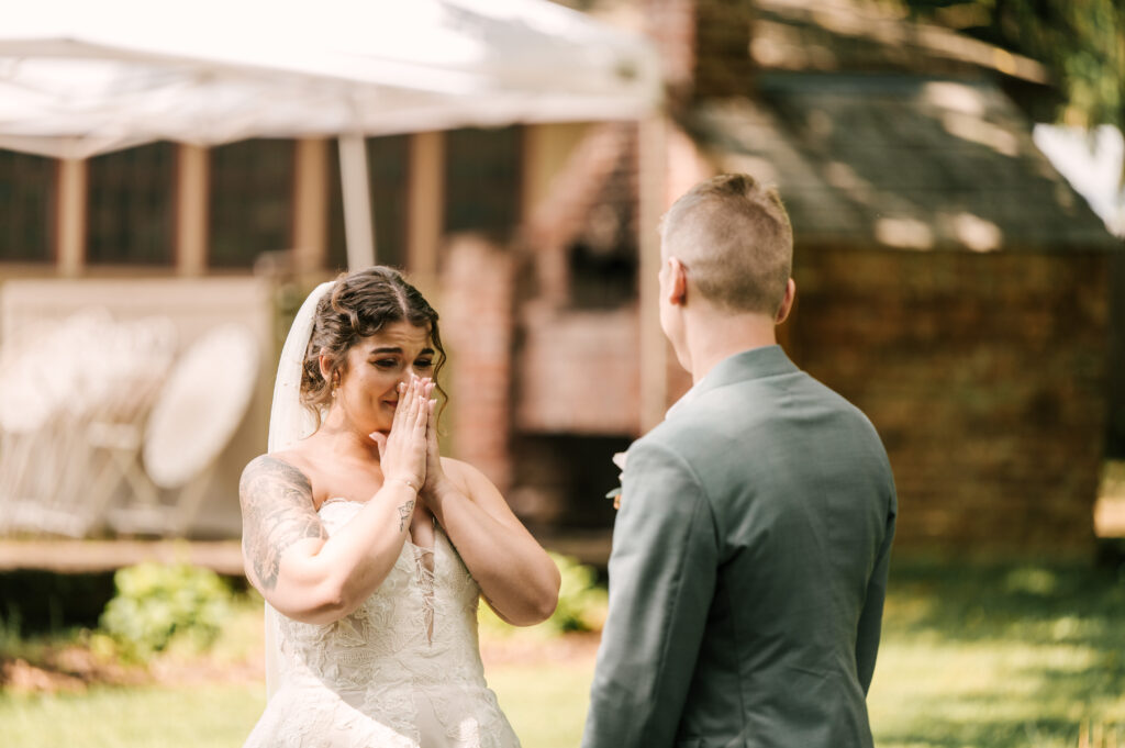 The bride crying as she looks at the groom during their first look at Waterloo Village.