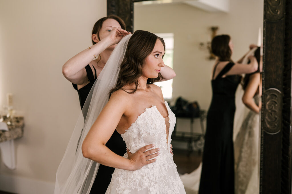 The maid of honor putting on the bride's veil at Perona Farms Refinery.