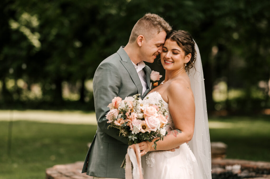The bride smiling as the groom nuzzles his head near her face at Waterloo Village.