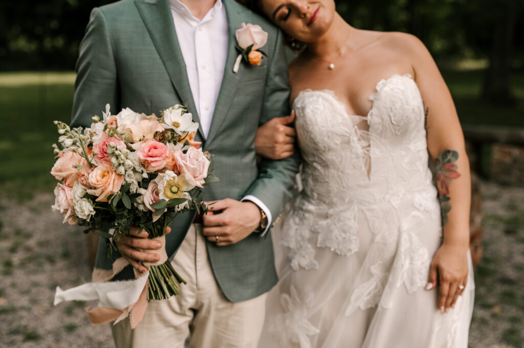 The bride holding on to the groom's arm as she leans on him at Waterloo Village.