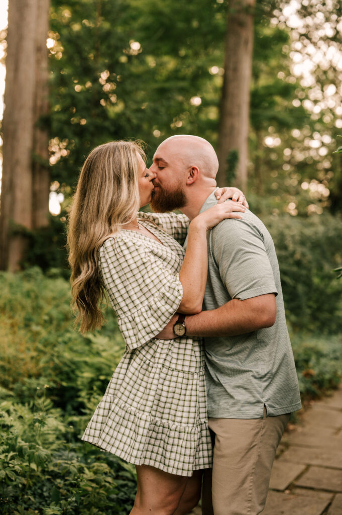 The newly engaged couple sharing a kiss on a walkway at Skylands Manor.